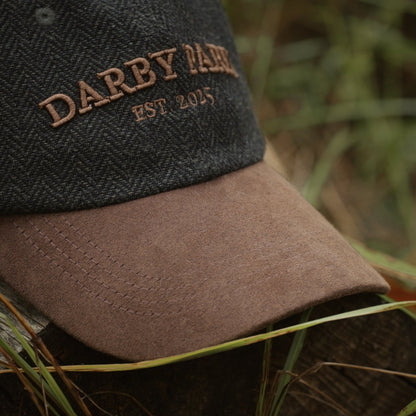 Close-up of the embroidered Darby Park, Est. 2025 wordmark and brown faux suede brim on the Tweed Cap.