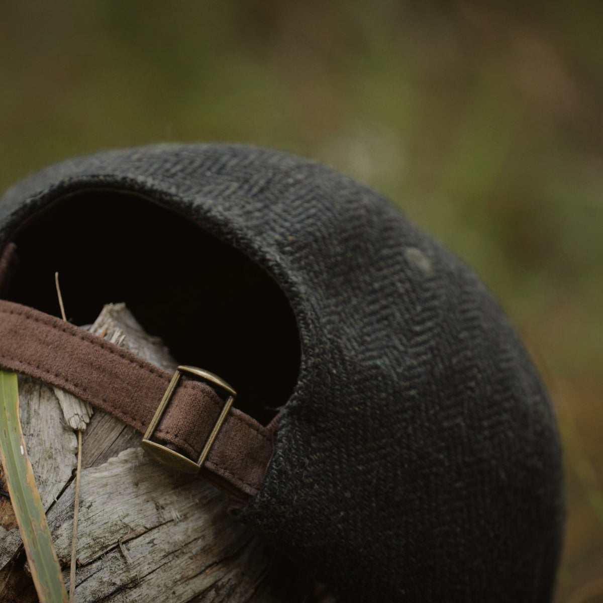 Back of the Tweed Cap showing the adjustable brown strap and brass-tone metal clasp.
