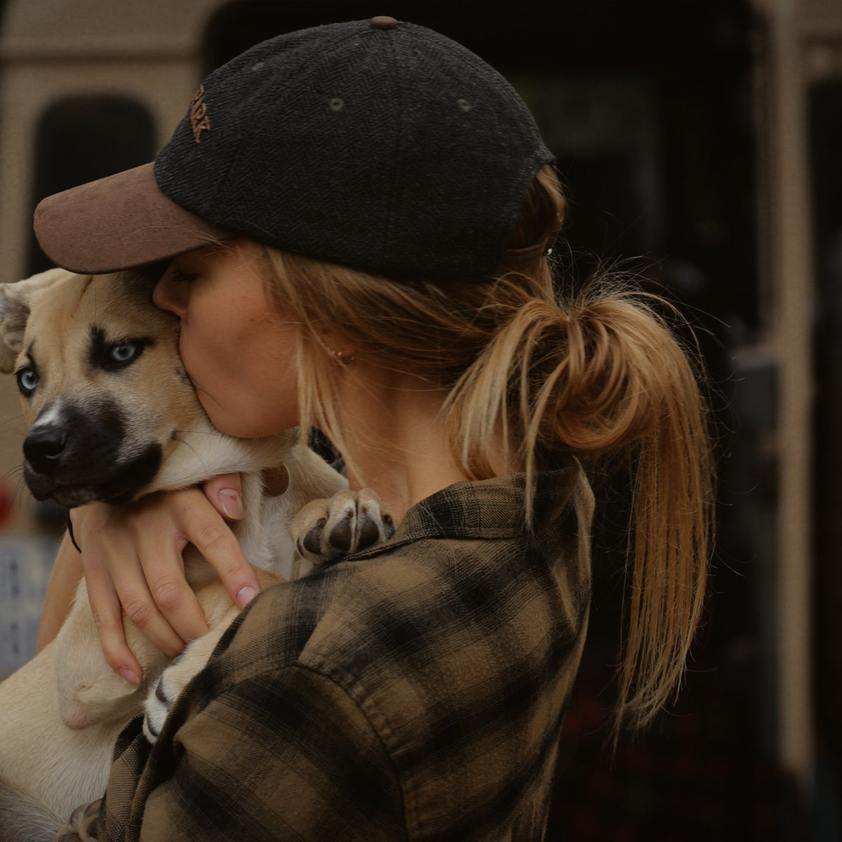 Woman in the Tweed Cap and a plaid flannel shirt hugging Winnie, the Darby Park dog.