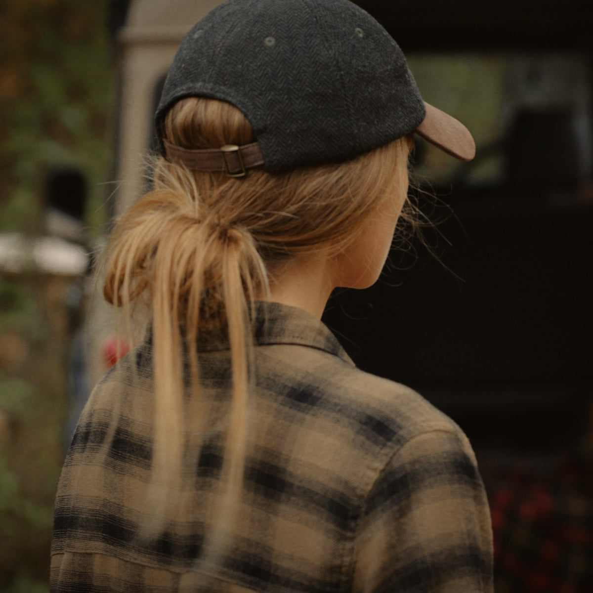 Back view of the Tweed Cap worn with a low ponytail and a plaid flannel shirt.